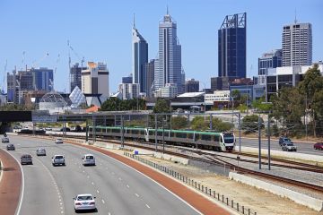 Perth City Skyline with train running down the middle of the freeway.