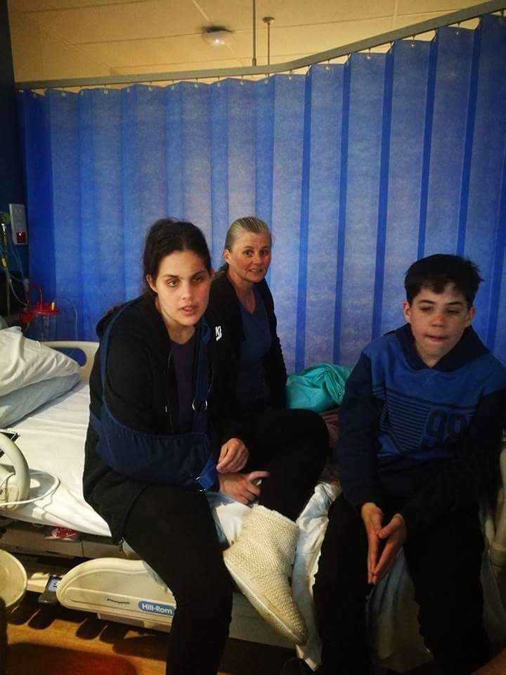 A young woman, Liz, sits on a hospital bed with her mum and brother following a catastrophic injury.