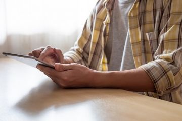 Person holding a tablet touching the screen