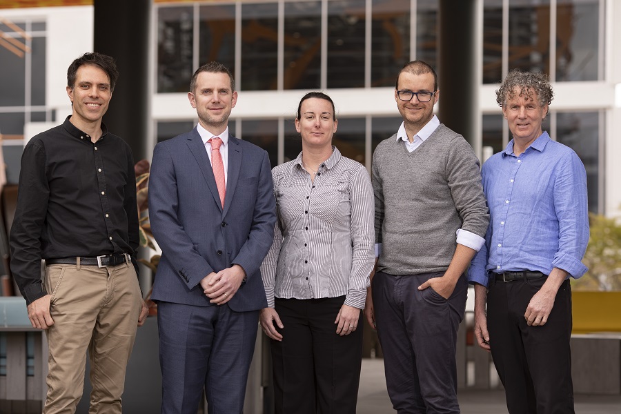 Two researchers from the cognitive functional therapy project standing and smiling with three insurance commission employee's